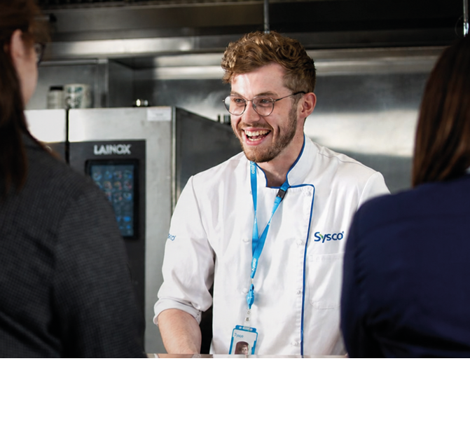 A man in a kitchen with a woman and another woman. Description generated by AI