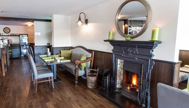 A restaurant with a fireplace and a mirror above it. Description generated by AI