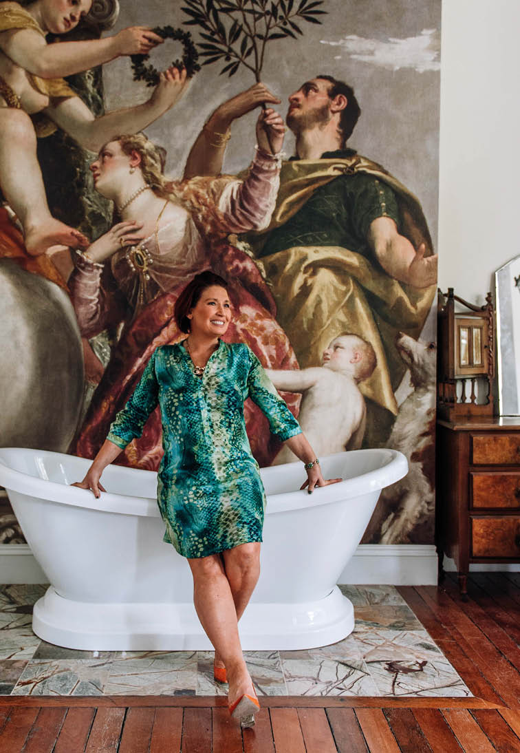 A woman is sitting in a bathtub with a painting of people above her. Description generated by AI
