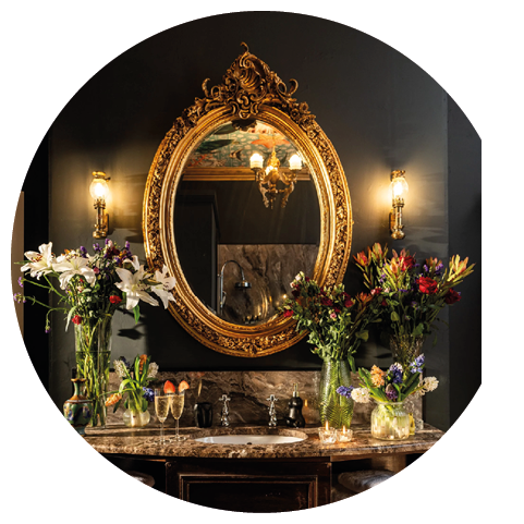 A bathroom vanity with a mirror and flowers. Description generated by AI
