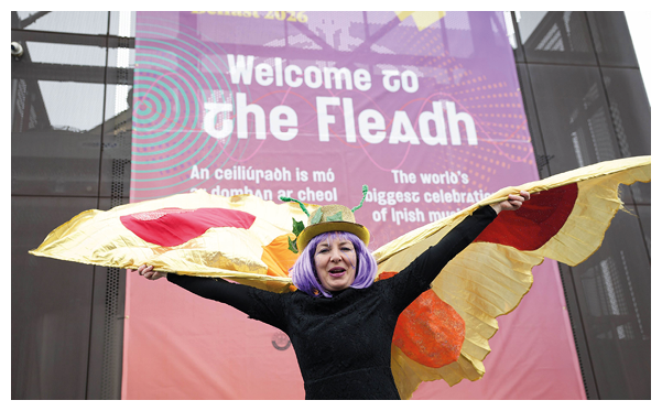 A woman wearing a purple wig and a black shirt is holding a kite that has a yellow and red tail. Description generated by AI