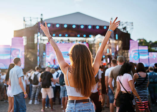 A woman with long hair and a white tank top is raising her arms in the air. Description generated by AI