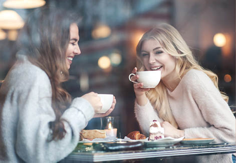Two girl friends drinking coffee in the cafe
