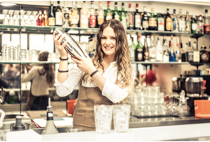 Pretty barmaid shaking cocktails in a bar - Female bartender preparing drinks for guests