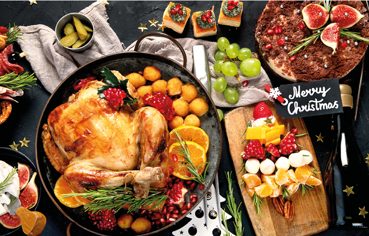Christmas dinner with roast chicken, christmas wreath, tree, cake, snacks, cheese and champagne on a black background. Top view.
