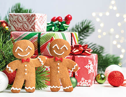Two gingerbread men are smiling and holding hands in front of a stack of presents. The scene is festive and joyful, with the gingerbread men representing the spirit of Christmas