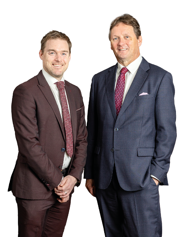 Two adults wearing suits and ties stand side by side smiling against a white background. Description generated by AI
