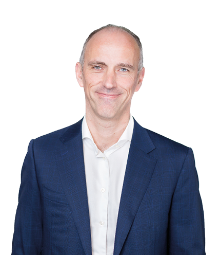 A person with short hair wearing a dark blue suit and white shirt is smiling against a plain white background. Description generated by AI