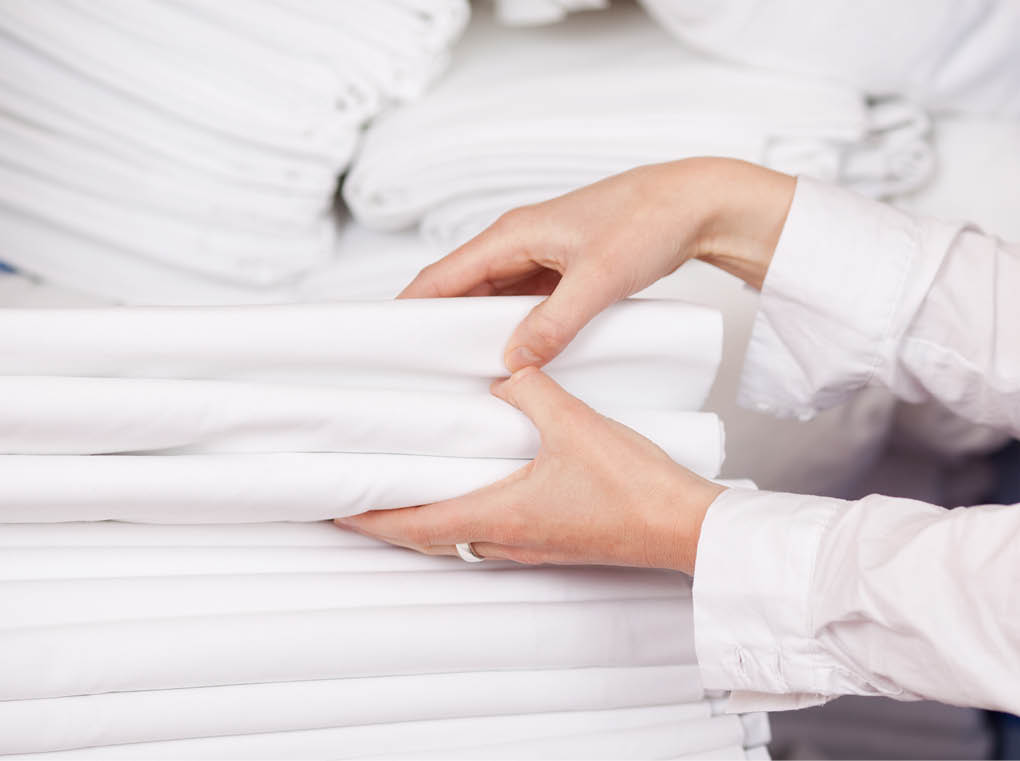 Closeup of white bedsheets stacked in store room of hotel