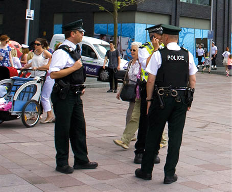 All in a day's work. Armed Police patrol Belfast's modern and buzzing Titanic Quarter during the Tall Ships visit in July 2015. This is normal uniform for the Police Service of Northern Ireland. PSNI 