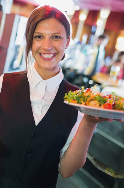 Pretty barmaid holding plates of salads in a bar