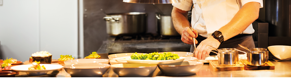 Chef standing in a restaurant kitchen, plating food.