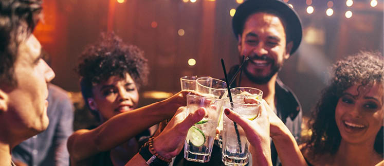 Group of friends having drinks at the night club party. Young people enjoying at a bar toasting cocktails.