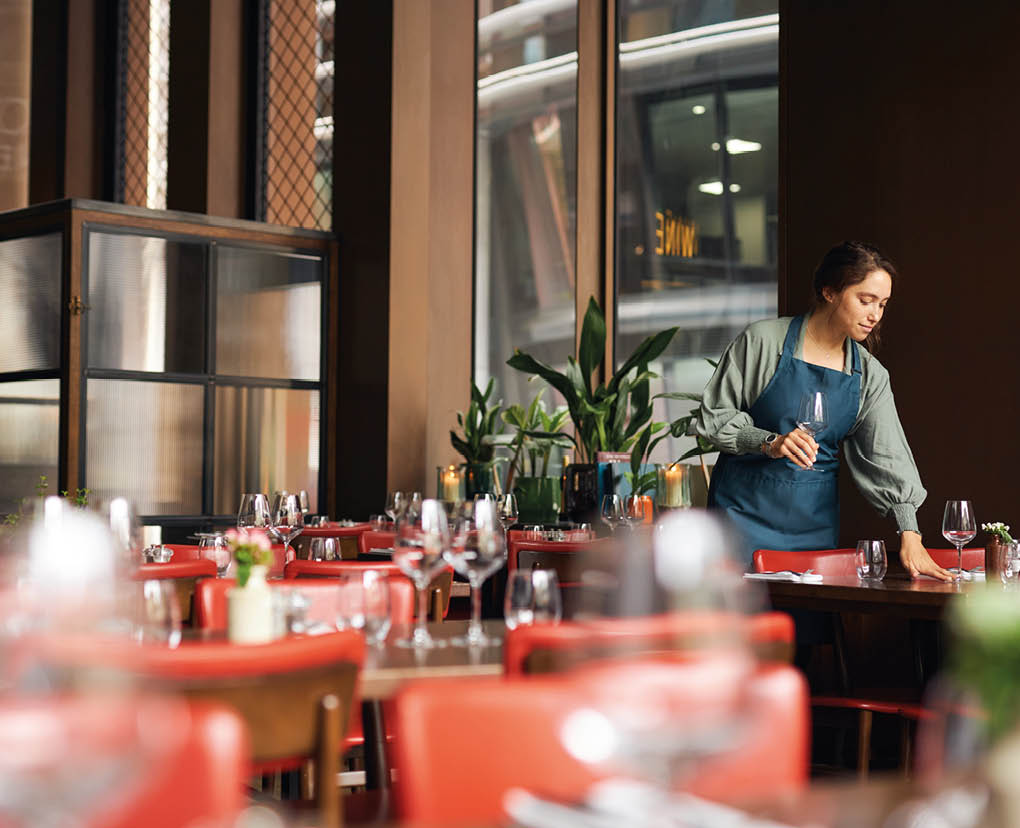 Female waitress setting tables in restaurant 