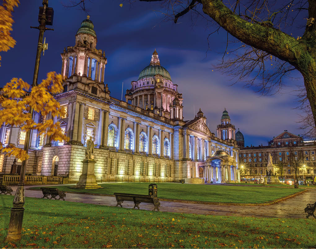 The beautiful City Hall of Belfast illuminated at twilight with some autumnal trees