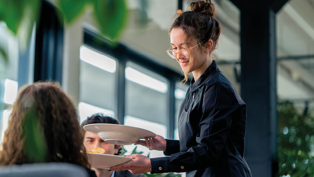 a girl waiter serves orders to guests the concept of hospitality and service in high-class restaurant